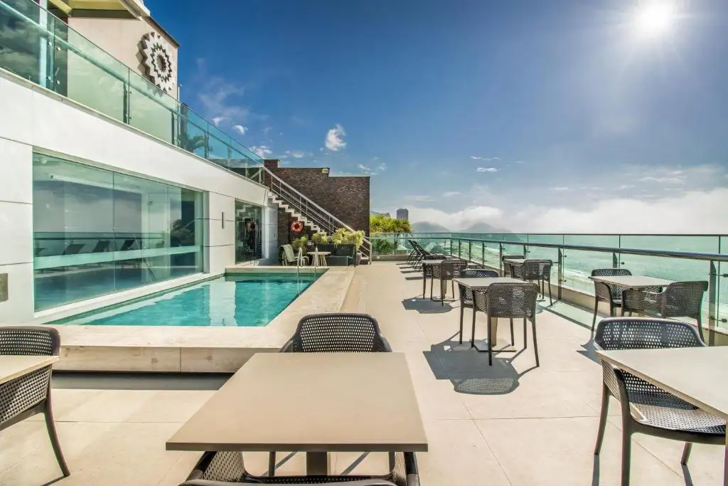 um pátio externo com mesas e cadeiras e uma piscina em Arena Copacabana Hotel no Rio de Janeiro