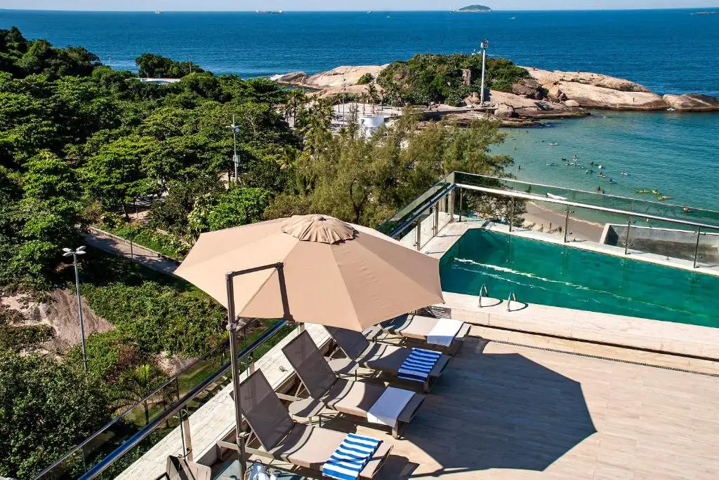 um pátio com guarda-sol e cadeiras e o oceano em Arena Ipanema Hotel no Rio de Janeiro