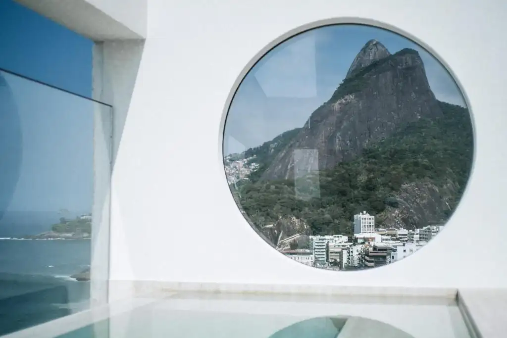 Circular window at JANEIRO Hotel framing Dois Irmãos and the Leblon coastline