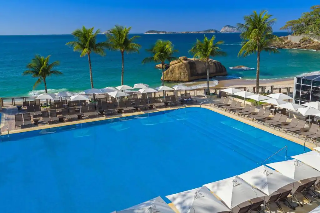 an overhead view of a swimming pool with chairs and the ocean at Sheraton Grand Rio Hotel & Resort in Rio de Janeiro