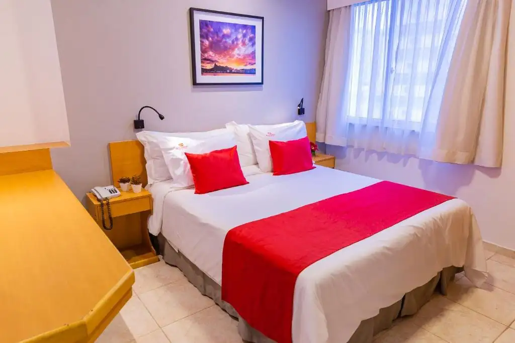 um quarto de hotel com uma cama grande e travesseiros vermelhos em Hotel Vermont Ipanema no Rio de Janeiro