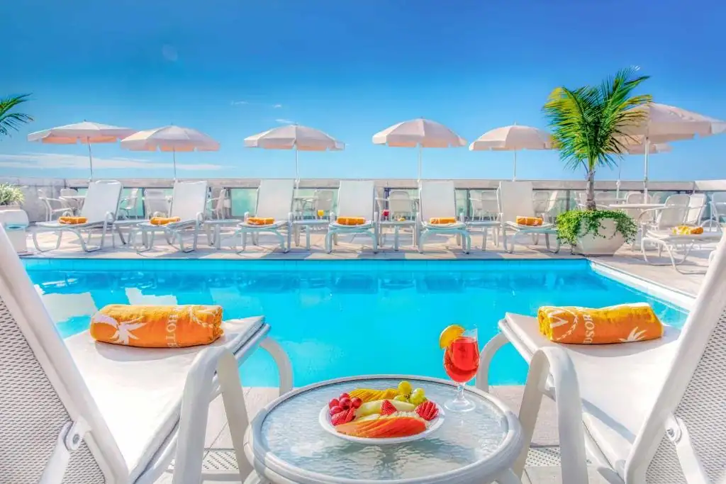 uma piscina de resort com cadeiras e uma mesa com frutas. em Windsor Excelsior Copacabana no Rio de Janeiro