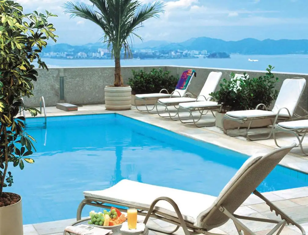 a swimming pool with chairs and a table with food on it at Windsor Guanabara Hotel in Rio de Janeiro