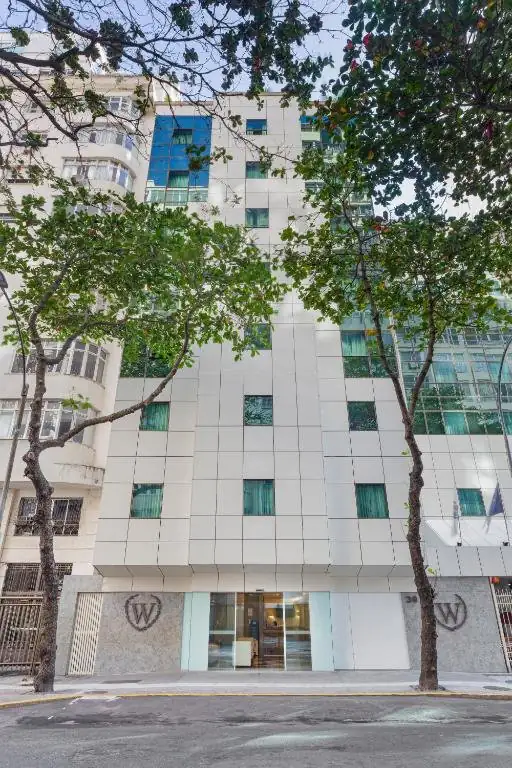 um prédio alto e branco com árvores em frente a ele em Windsor Martinique Copacabana no Rio de Janeiro