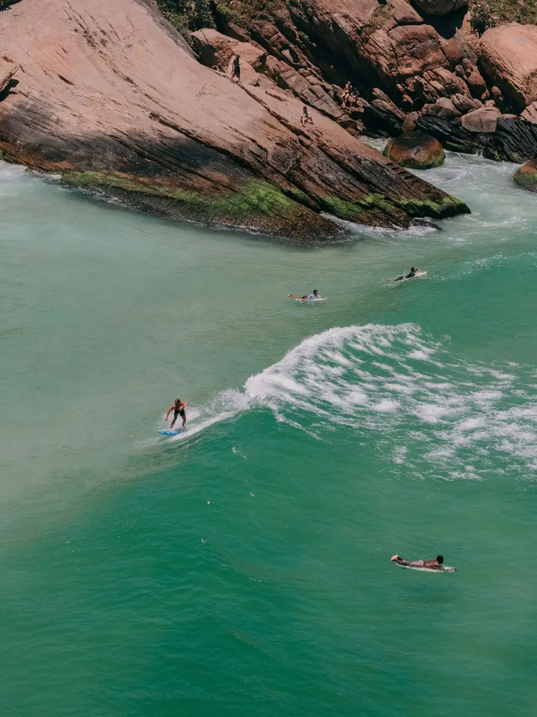 Surfers in the water beside Prainha's green coastline