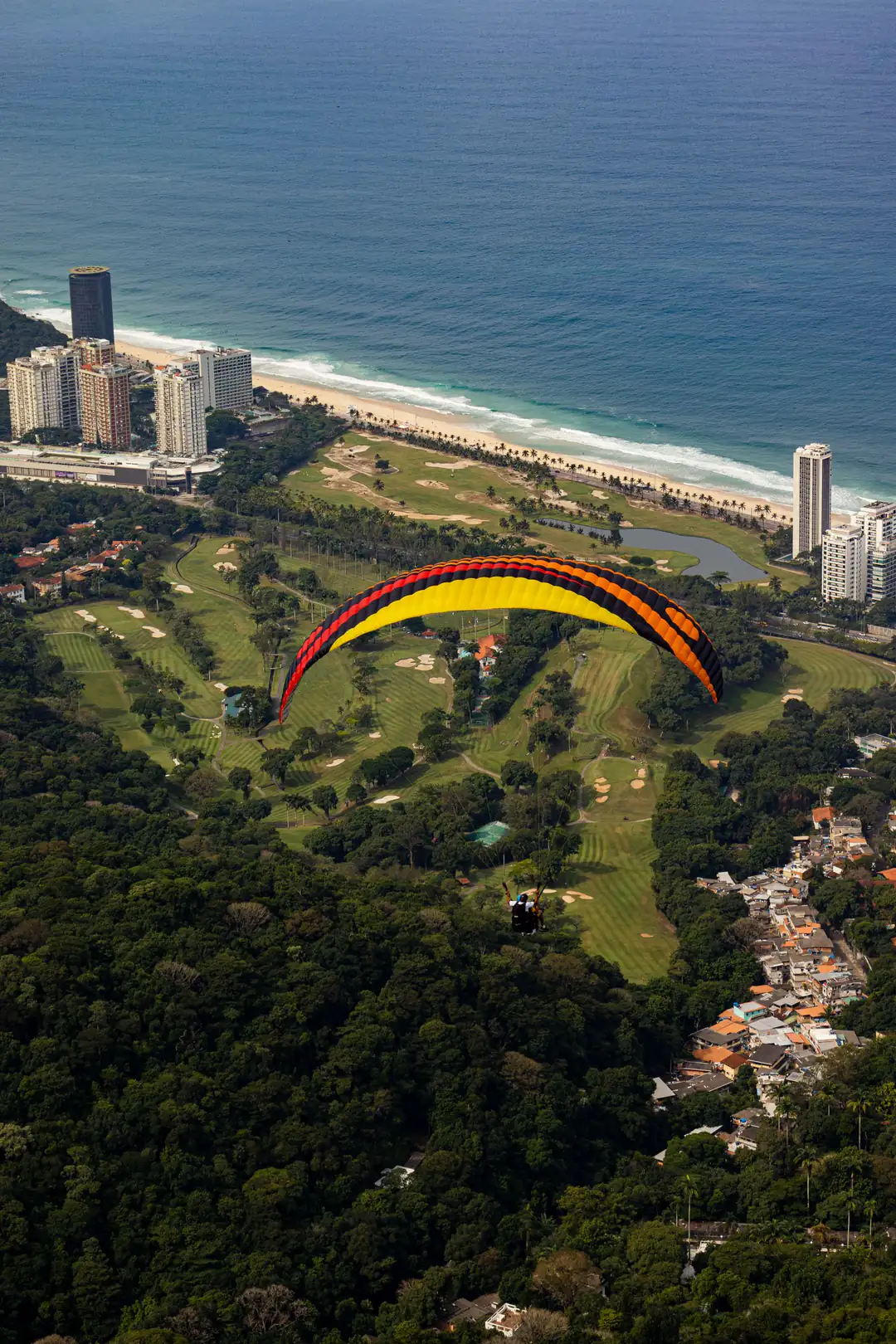 A paraglider flying above Rio de Janeiro's coastline