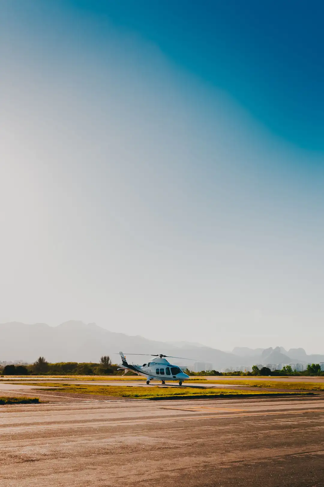 Sightseeing helicopter on the tarmac with Rio de Janeiro's mountains behind